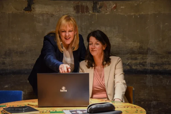 Two women in neat office clothing looking at a laptop screen